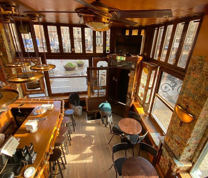 The wooden Jolly Joker interior with tall windows overlooking Nieuwmarkt